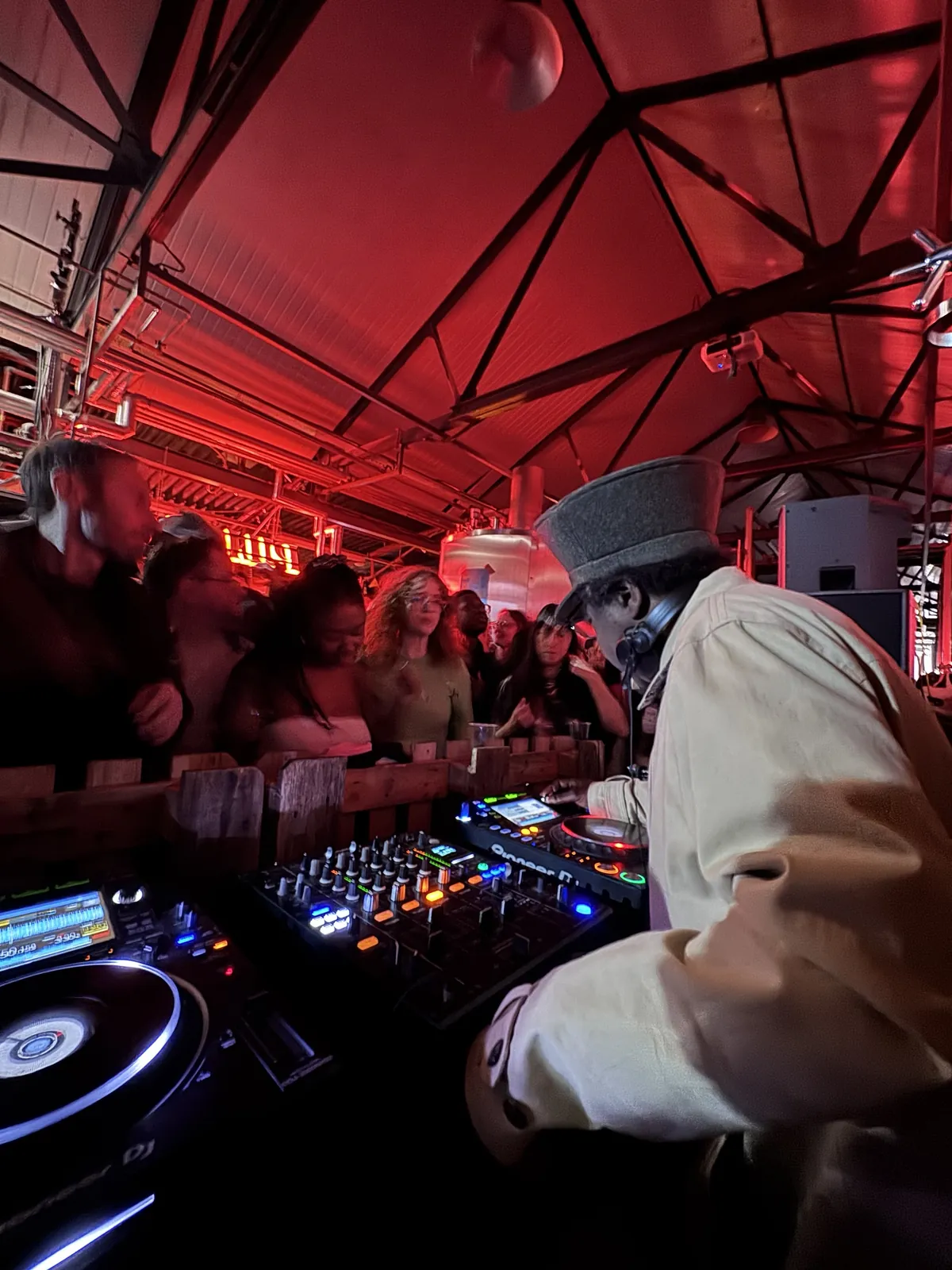 Norman Jay DJing on the Scruff Bag Sound System decks to a packed crowd under red lights